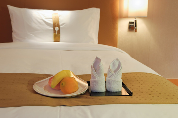 Serviettes et fruits au lit dans une chambre d'hôtel
 - Photo, image
