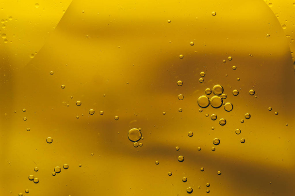 schönes Mischen von Wasser und Öl auf gelbem Hintergrund. - Foto, Bild