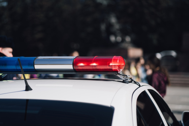 Zbliżenie Zdjęcia policyjnego samochodu z niebieskim i czerwonym syrena na dachu i rozmyte tle. - Zdjęcie, obraz