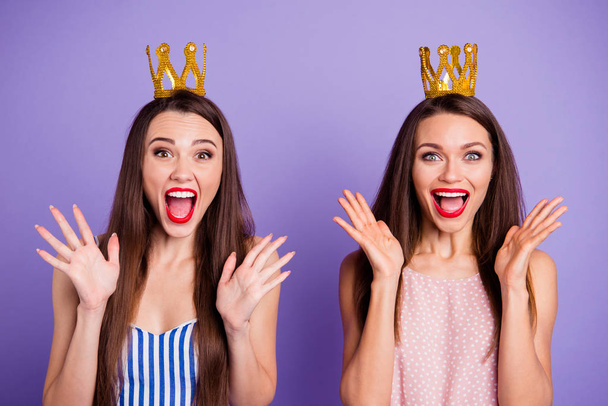 Close up portrait two people beautiful she her models chic ladies hands arms palms air power status gold crowns head yelling wear summer colorful dresses isolated purple violet bright background - 写真・画像