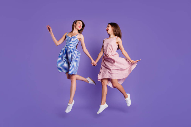 Full length body size photo two people beautiful funky she her models ladies hold hands jump high best shopper shopping mall shop store wear summer dresses isolated purple violet background - Photo, image