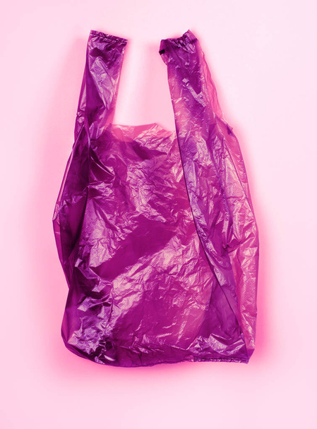 Purple plastic shiny package on pink background. - Foto, Imagen
