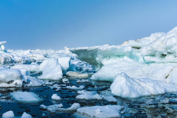 Дрейфующий лед в море у песчаного берега. Лед в море рядом с пляжем
 - Фото, изображение
