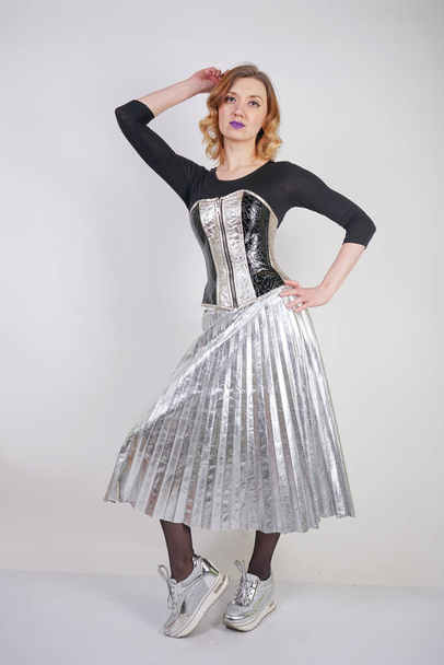 piękna kaukaski dziewczyna ubrana w futurystyczny PCV gorset i kratka metalowa spódnica z lustrzanymi butami do biegania na białym tle w studiu - Zdjęcie, obraz