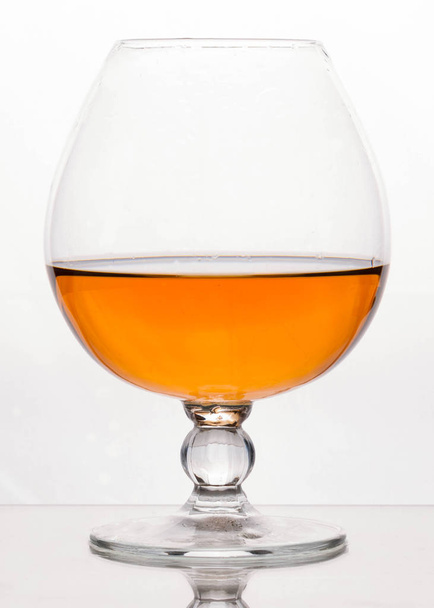 side view of crystal glass with brown cognac on white background with copy space - Photo, image