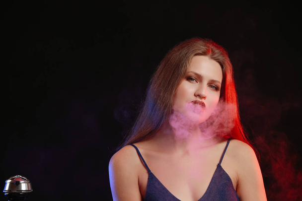 Joven mujer fumando narguile sobre fondo oscuro
 - Foto, imagen