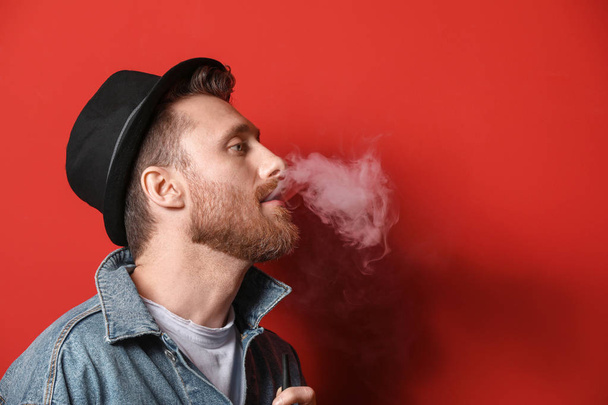 junger Mann raucht auf farbigem Hintergrund - Foto, Bild