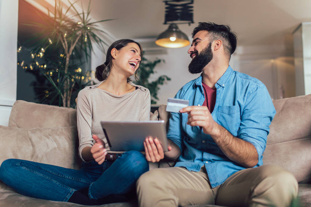 Uśmiechający się para w domu przy użyciu cyfrowego tabletu i karty kredytowej - Zdjęcie, obraz