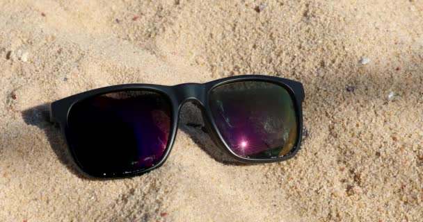 Reflexionando gafas de sol negras en la arena de la playa, verano - Vista de cerca - Resolución DCi 4K
 - Metraje, vídeo