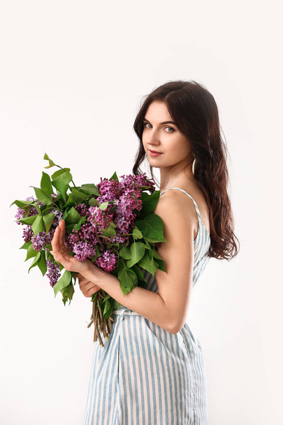 Beautiful young woman with bouquet of lilac flowers on white background - Fotó, kép