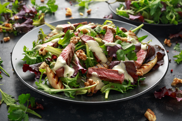 Grilled Beef Steak salad with pears, walnuts and greens vegetables and blue cheese sauce. healthy food. - Photo, Image