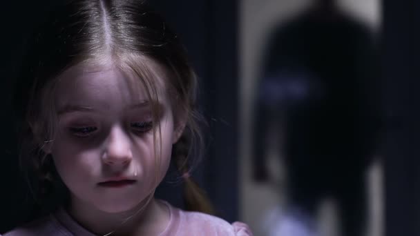 niedliches kleines Mädchen weint, hat Angst vor dem grausamen Vater, der sich im Hintergrund nähert - Filmmaterial, Video