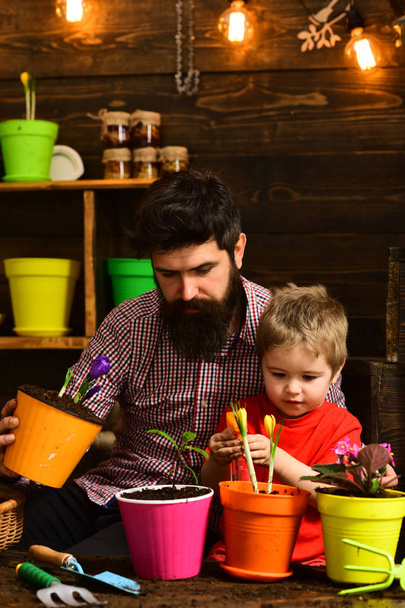 Father and son. Fathers day. Flower care watering. Soil fertilizers. Family day. Greenhouse. bearded man and little boy child love nature. happy gardeners with spring flowers. Confidence in mind - Фото, зображення