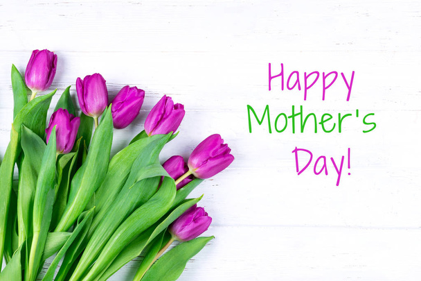 lila violette Tulpensträuße auf weißem Holzhintergrund. Glückliche Grußkarte zum Muttertag. - Foto, Bild