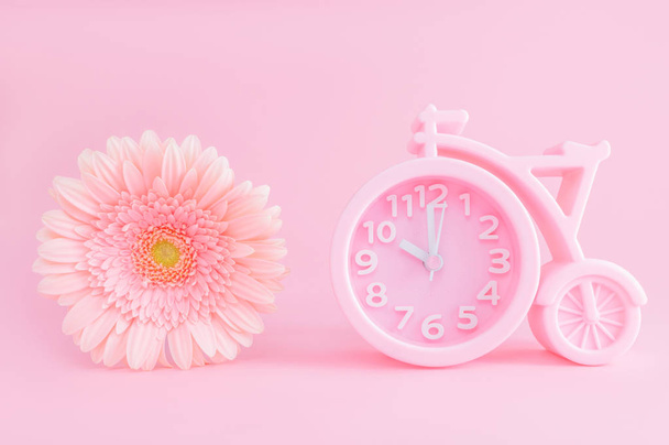 Pink alarm clock and gerbera flower on pink background. Good morning concept. Postcard with copy space. - Φωτογραφία, εικόνα