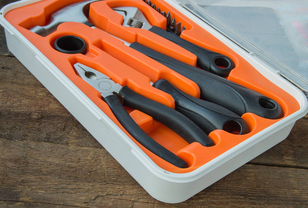Kit utensili pinze, martello, cacciavite in custodia di plastica arancione su vecchia tavola di legno con copyspace
 - Foto, immagini