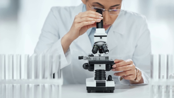 επιλεκτική εστίαση του αφρικανικού αμερικανού επιστήμονα σε γυαλιά που αναζητούν δείγμα μέσω του μικροσκόπιο στο εργαστήριο  - Πλάνα, βίντεο