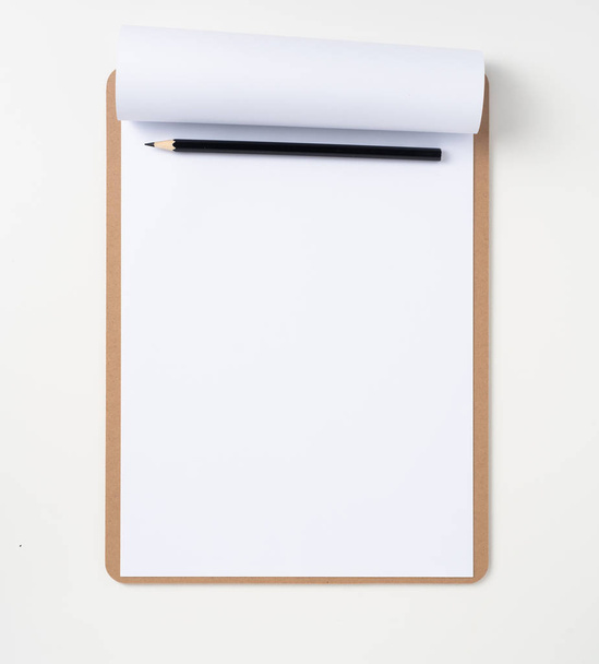 A4 flipped paper on brown clipboard with black pencil on white background for mockup. - Foto, imagen