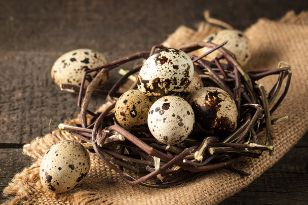 Huevos de codorniz en un nido sobre un fondo rústico de madera. Concepto de comida saludable - Foto, Imagen