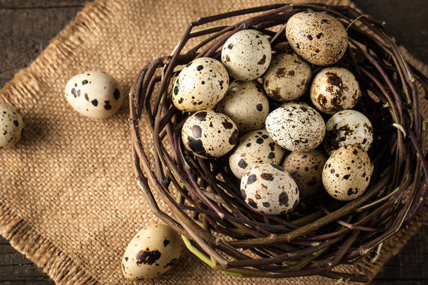 przepiórcze jaja w gnieździe na rustykalnym drewnianym tle. Koncepcja zdrowej żywności - Zdjęcie, obraz