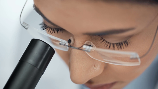 vista de cerca del científico afroamericano concentrado en gafas usando microscopio
 - Metraje, vídeo