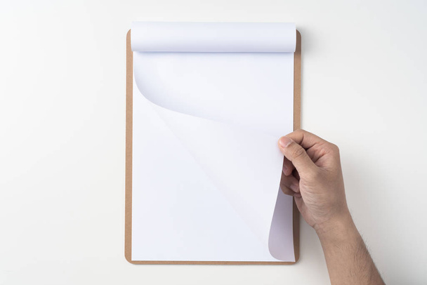 Top view of man hand holding white A4 flipped paper on brown clipboard isolated on white background - Φωτογραφία, εικόνα