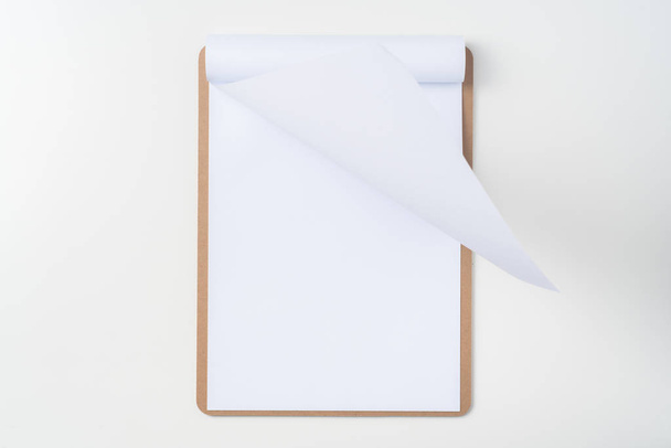 Κορυφαία όψη του λευκού ανεστραμμένο χαρτιού A4 σε καφέ πρόχειρο απομονωμένο σε λευκό φόντο για Μαμέ. - Φωτογραφία, εικόνα