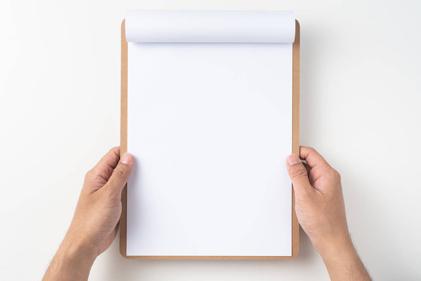 Man hands holding white A4 flipped paper on brown clipboard isolated on white background - Φωτογραφία, εικόνα