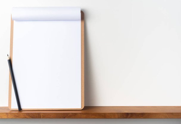 A4 flipped paper on brown clipboard with pencil on shelf on white background for mockup. - Photo, image