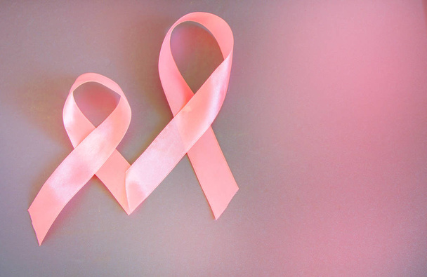Twee roze linten om de bewustwording over borstkanker, de afbeelding op een grijze achtergrond, kopiëren ruimte - Foto, afbeelding