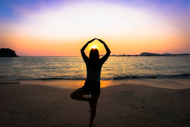 Siluetti nainen jooga rannalla auringonlaskun yli
 - Valokuva, kuva