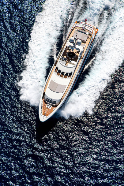 Повітряний вид зверху фото розкішної яхти, що рухається на швидкості у відкритому морі з бризкою і хвилею
 - Фото, зображення