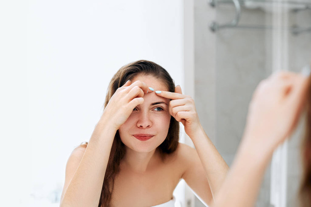 Young woman  looking and squeeze  acne on a face in front of the mirror. Ugly problem skin girl, teen girl having pimples. Skin care. Beauty - Φωτογραφία, εικόνα