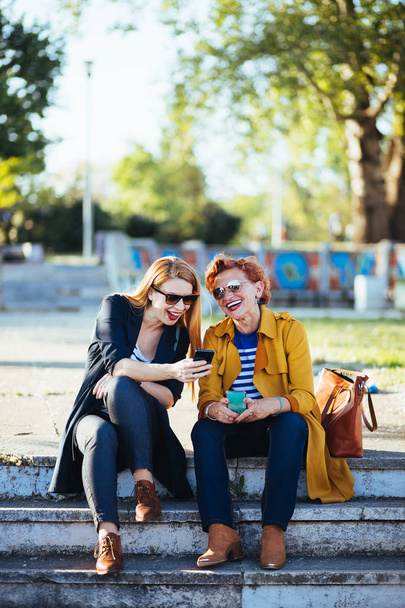 Matka i córka w parku udostępnianie treści na swoich smartfonach - Zdjęcie, obraz
