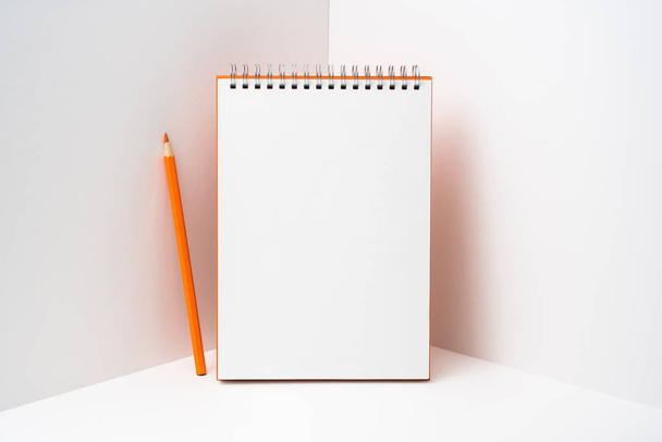 Відкритий оранжевий спіральний блокнот з олівцем. Стаціонарний на білому тлі з простором для копіювання
. - Фото, зображення