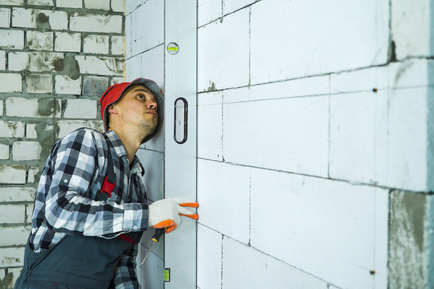 будівельник натискає на рівень бульбашки, щоб блокувати стіну вертикально перевіряючи її якість
 - Фото, зображення