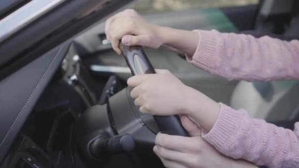 Close-up of the hands of the father and daughter sitting behind the wheel of a luxury car. Father teaches girl to drive a vehicle. - Video, Çekim