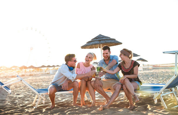 Gelukkige Millenial vriendengroep plezier op strand partij drinken fancy cocktails bij zonsondergang-zomer vreugde en vriendschap concept met jonge mensen op vakantie-warme zon gefilterde kleur tonen - Foto, afbeelding