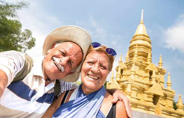 サムイ島の黄金の寺院で自分撮りをするシニアカップル - タイの不思議に旅行する幸せな退職者 - 東南アジアの目的地に世界中のアクティブな高齢者の概念と楽しみ - 写真・画像
