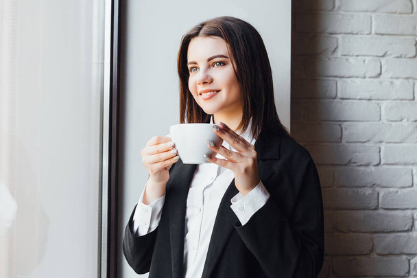 beautiful businesswoman with cup of coffee, focus on foreground - Foto, Bild