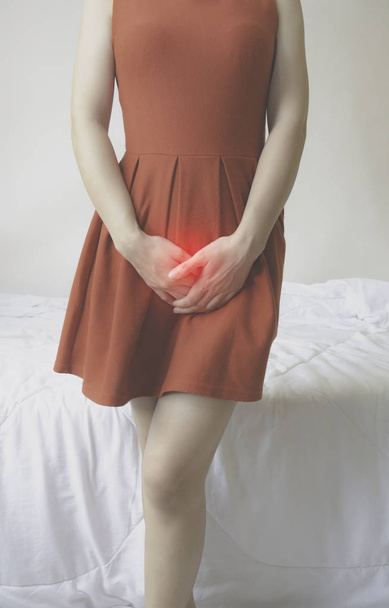 Las mujeres usan falda roja Use la mano para rascarse la vagina.Comezón genital causado por hongos en la ropa interior.No se enfoque en objetos
. - Foto, imagen