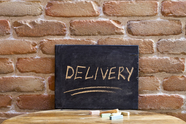 Chalk board with the word DELIVERY drown by hand on wooden table - Fotografie, Obrázek