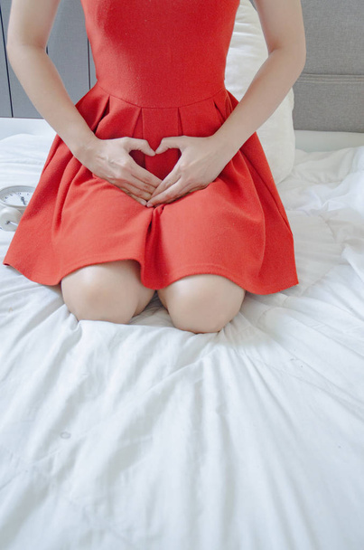 Женщины носят красную юбку Используйте руку, чтобы почесать вагина.Генитальный зуд, вызванный грибком в нижнем белье .Do не сосредоточиться на объектах
. - Фото, изображение
