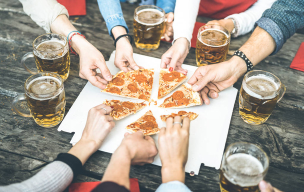 Millenial friends group drinking beer and sharing pizza slices at bar restaurant - Friendship concept with young people having fun together eating snack at risto pub pizzeria - Vintage contrast filter - Foto, Bild