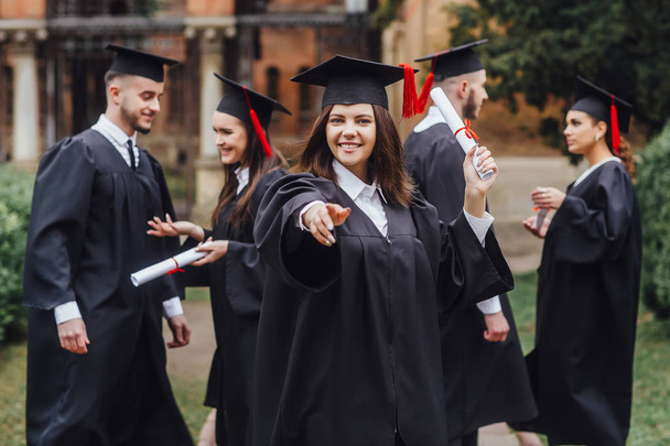 groupe d'étudiants internationaux heureux dans des panneaux de mortier et robes de célibataire avec des diplômes
 - Photo, image