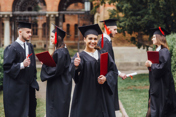 Estudantes com diplomas, foco em primeiro plano
 - Foto, Imagem
