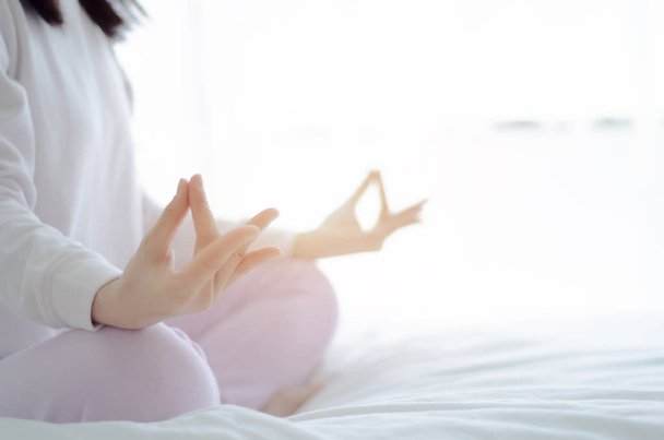 Yoga üzerine oturan Asyalı kızlar sıcak bir sabah yatakta pozlar. Sıcak bir ton. Nesnelere odaklanma. - Fotoğraf, Görsel