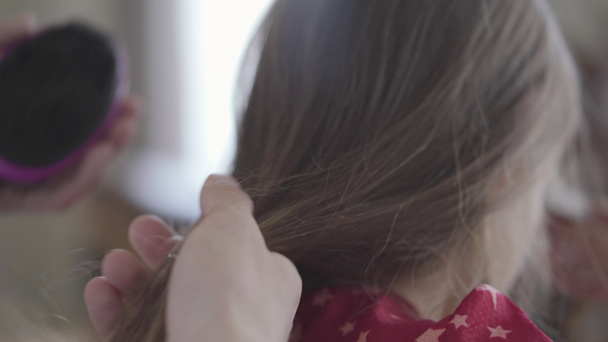 Hands of the father slowly brushing the long hair of his little girl close up. Family leisure. Fatherhood, caring, parenthood, love. Back view - Materiał filmowy, wideo