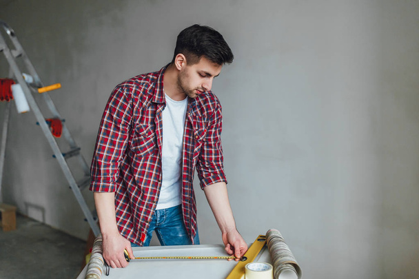 Young man doing repairs at home and using measure - Φωτογραφία, εικόνα