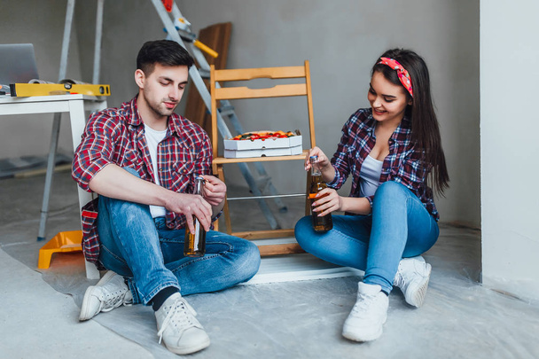 Lovely couple eating pizza and drinking beer in new apartment - Fotografie, Obrázek